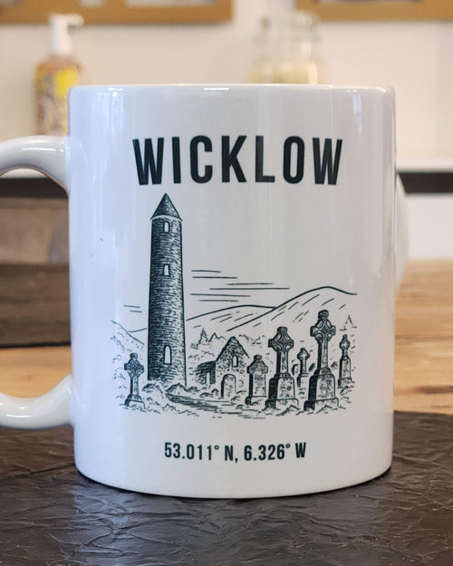 White mug with black text and graphics on a wooden surface