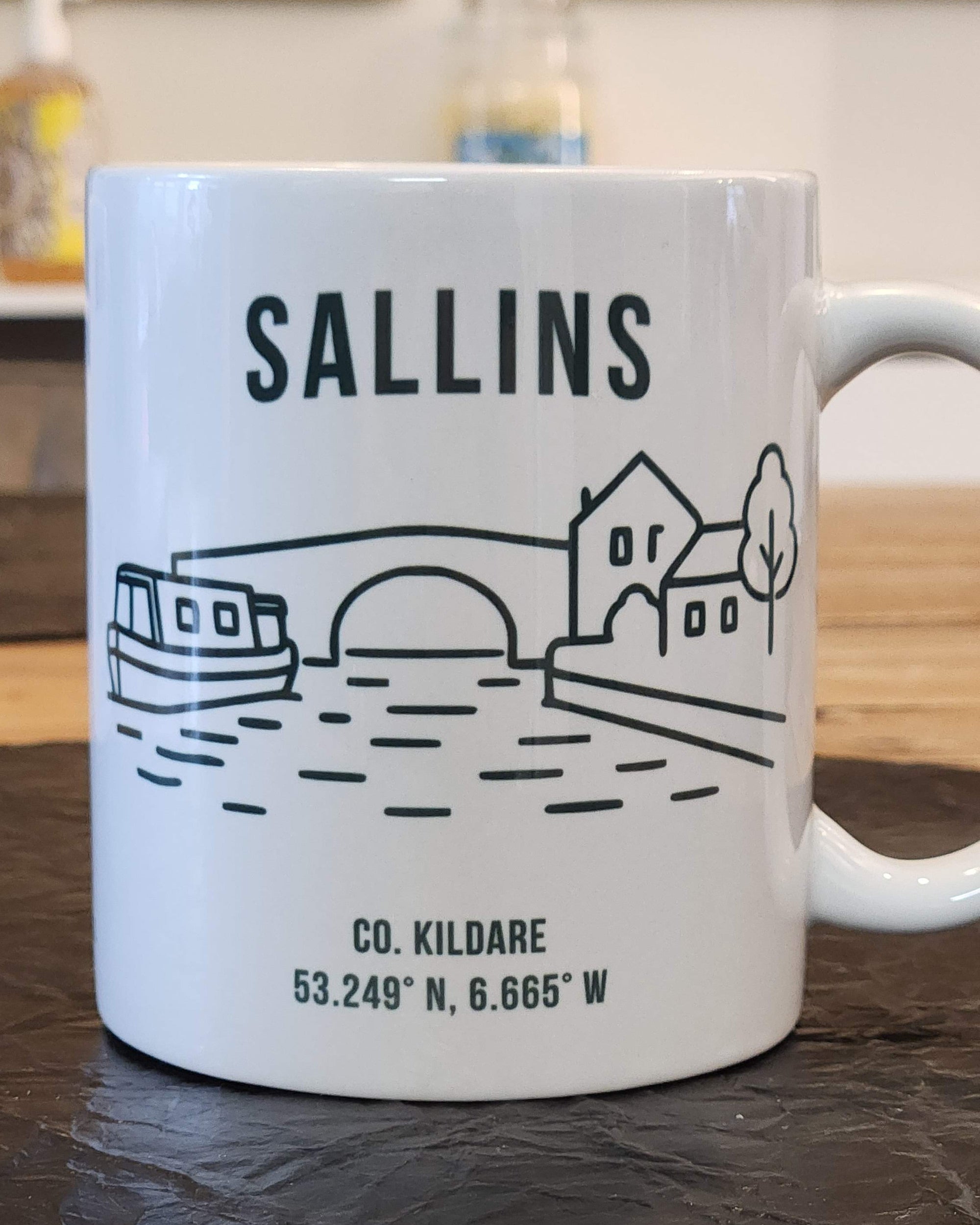 White mug with black text and graphics on a wooden surface