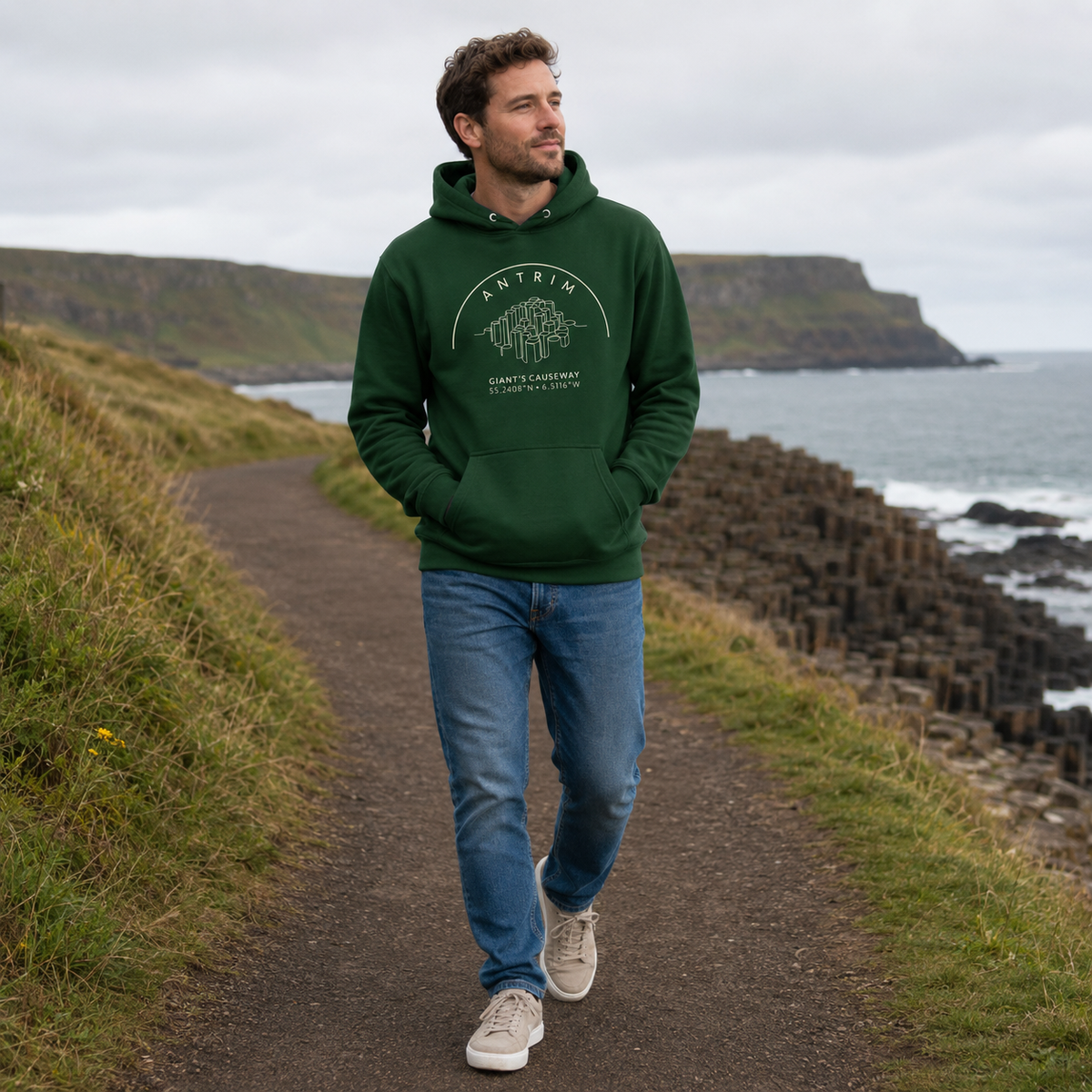 Man wearing the Antrim Giant’s Causeway forest green hoodie on the Antrim coast