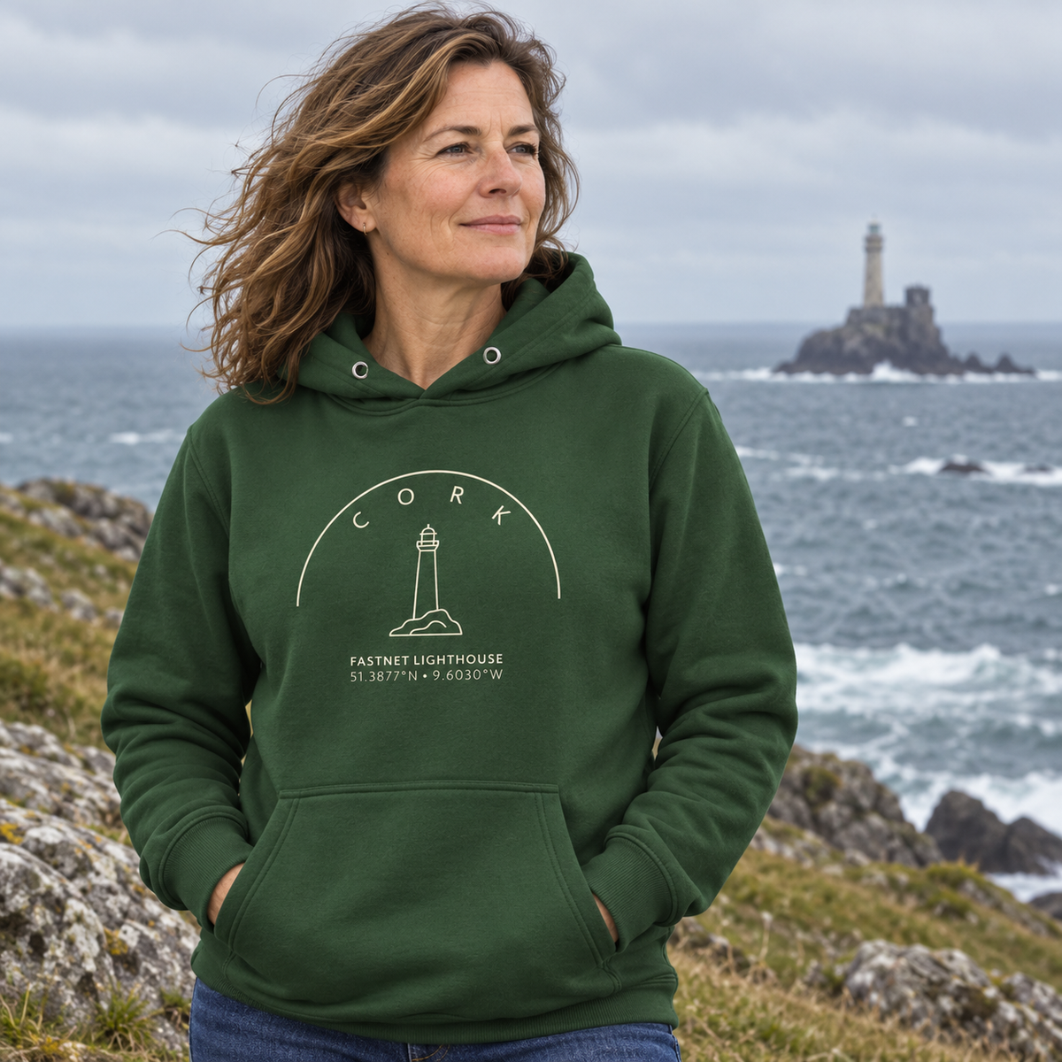 Woman wearing the Cork Fastnet Lighthouse forest green hoodie on the Cork coast