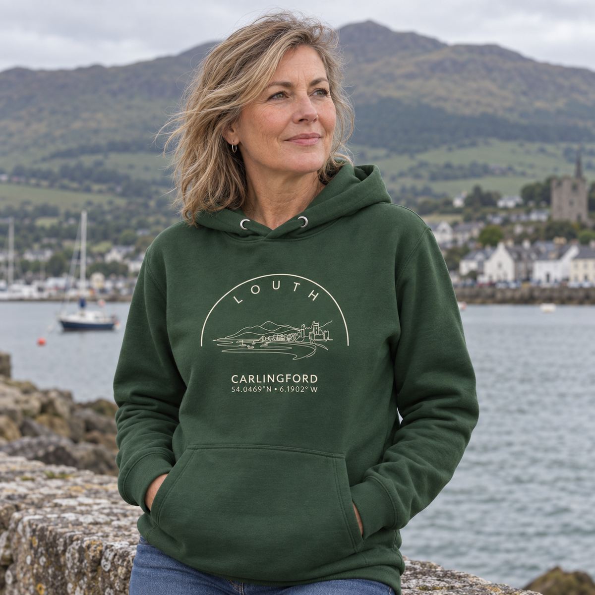 Woman wearing the Louth Carlingford forest green hoodie at Carlingford harbour